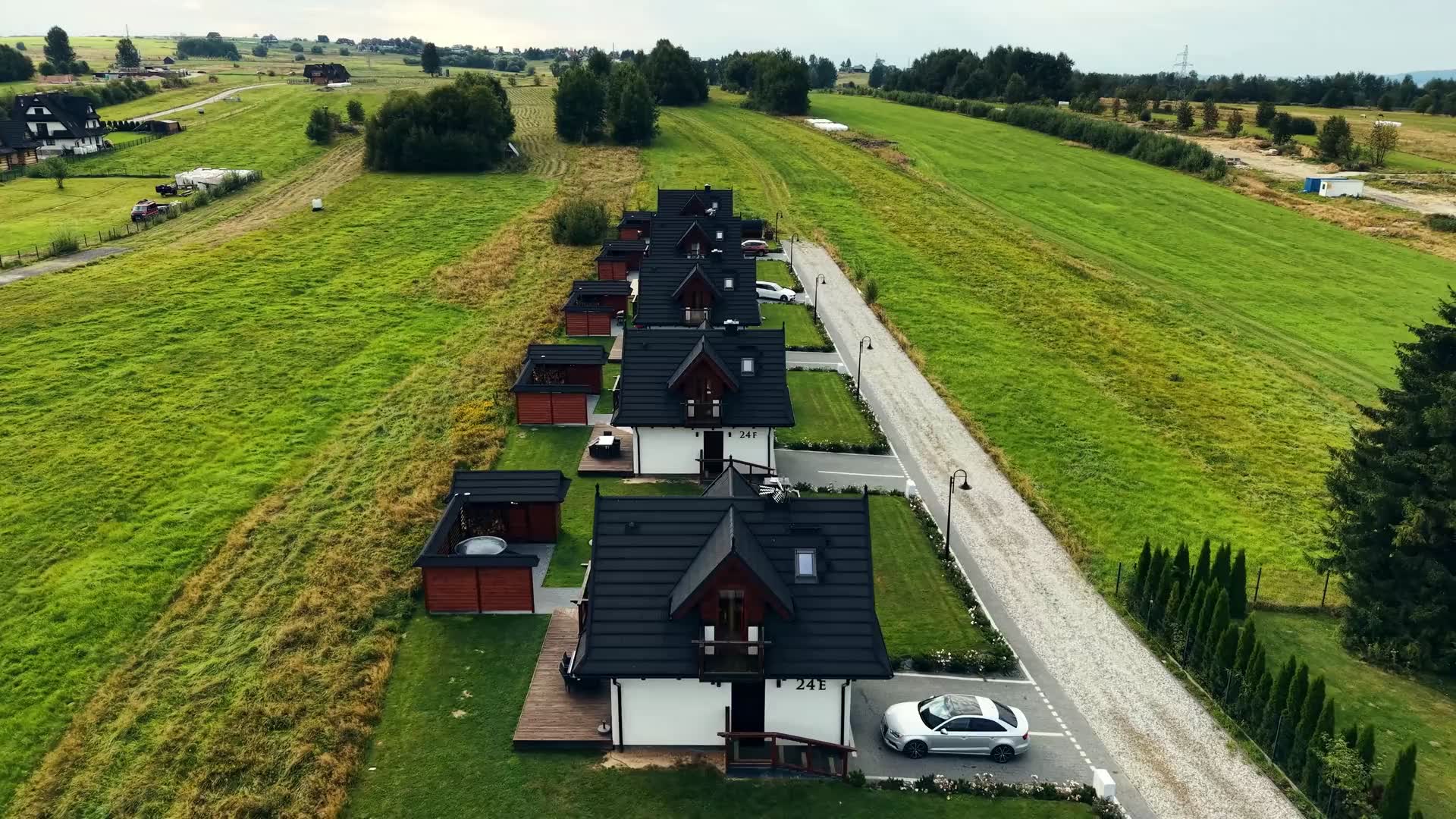 Rząd domków Korona Gór na łące w Białce Tatrzańskiej z lotu drona: domki z tarasem, balią i basenem