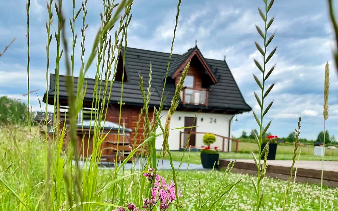 Domek Korona Gór widziany zza wysokich traw na łące