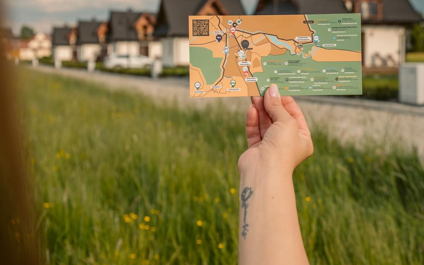 Mapa atrakcji Korona Gór w dłoni na tle domków