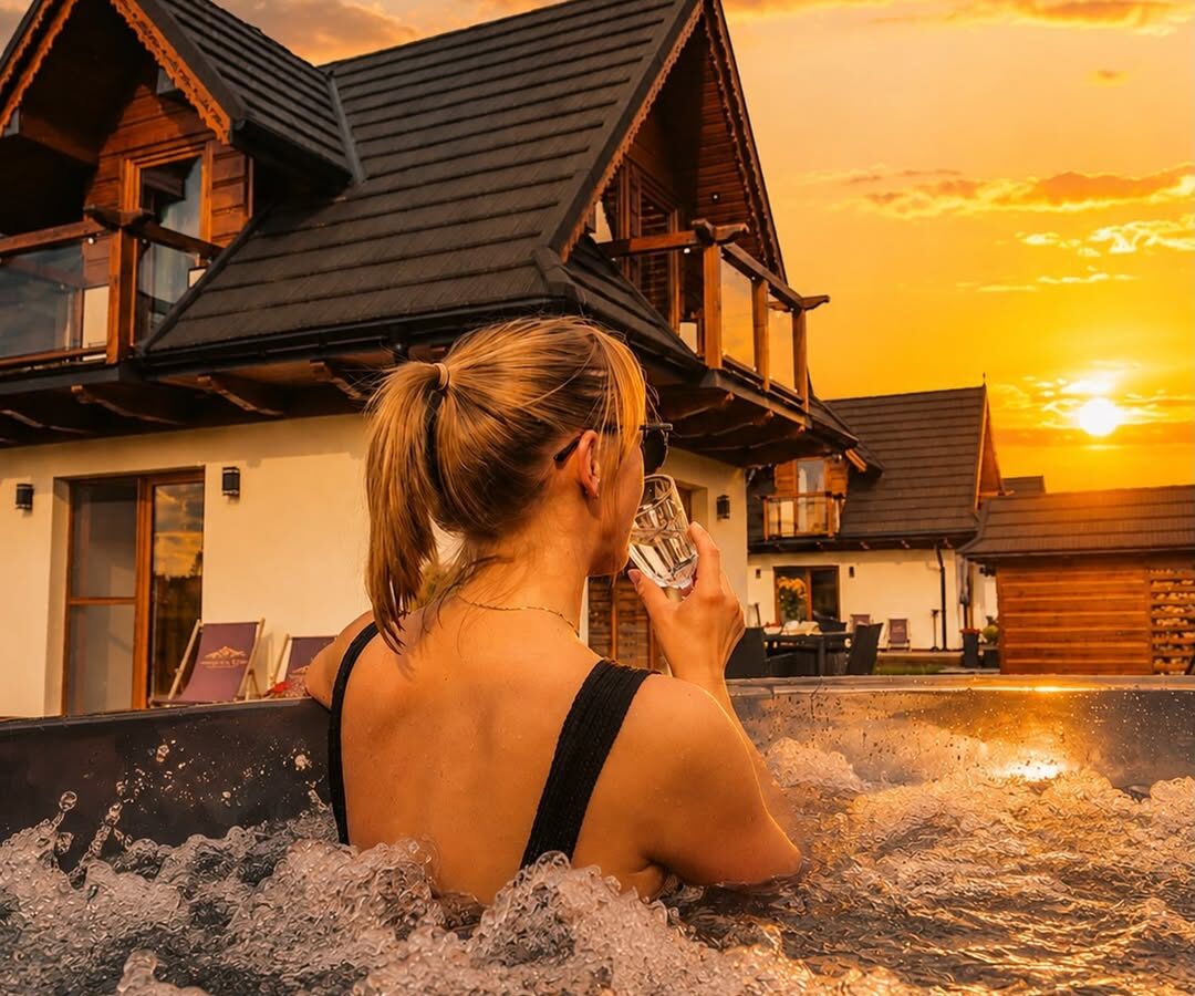 Kobieta w balii z hydromasażem przy domku o zachodzie słońca